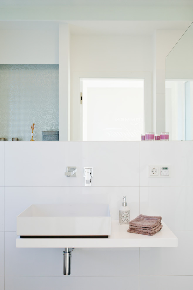 Imagen de aseo actual, de tamaño medio, con baldosas y/o azulejos blancos, paredes blancas, lavabo sobreencimera y baldosas y/o azulejos de cerámica