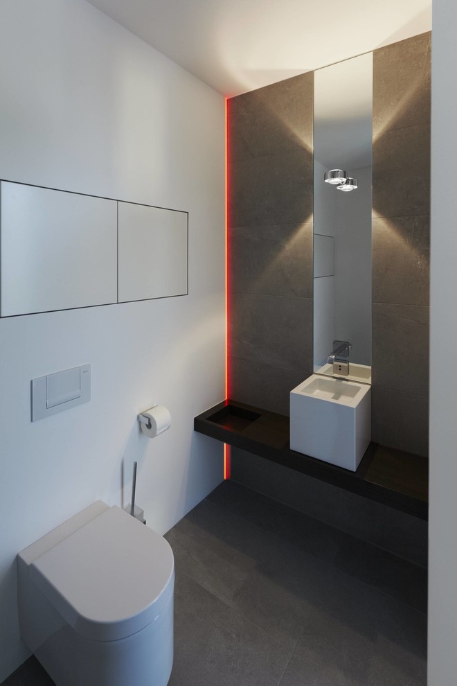 Moderne Gästetoilette mit Wandtoilette, grauen Fliesen, weißer Wandfarbe, Schieferboden und Aufsatzwaschbecken in Sonstige