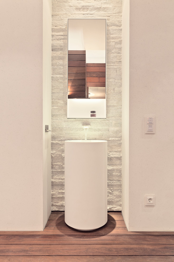 Kleine Moderne Gästetoilette mit weißer Wandfarbe, braunem Holzboden und Sockelwaschbecken in Essen