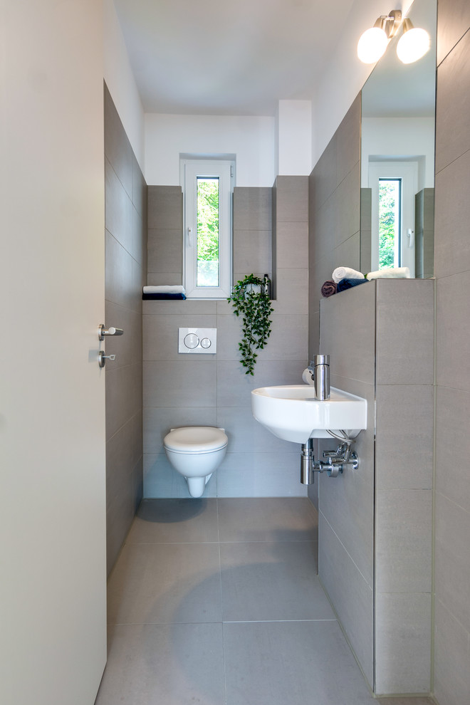 Example of a small danish beige tile and cement tile cement tile floor and beige floor powder room design in Hamburg with a wall-mount toilet, white walls and a wall-mount sink