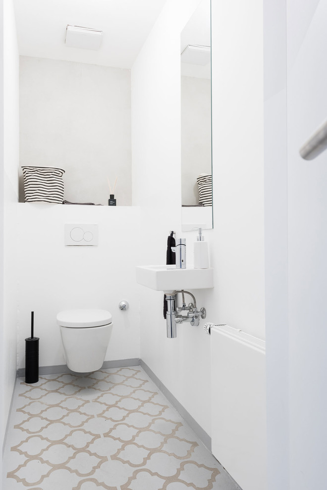 На фото: маленький туалет в современном стиле с инсталляцией, серой плиткой, белыми стенами, полом из керамической плитки и подвесной раковиной для на участке и в саду
