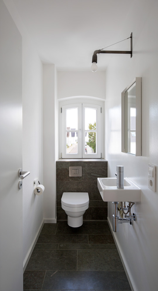 Idée de décoration pour un petit WC et toilettes design avec un carrelage gris, un mur blanc, un lavabo suspendu et un sol gris.
