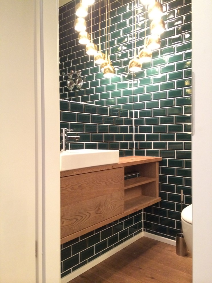 Idées déco pour un petit WC et toilettes contemporain en bois brun avec un carrelage vert, un carrelage métro, un mur vert, un sol en bois brun et une vasque.