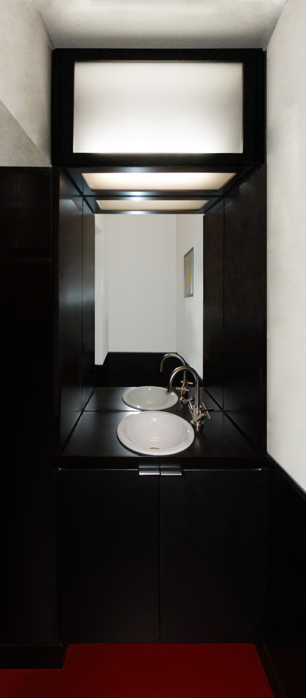 Foto på ett litet lantligt toalett, med ett nedsänkt handfat, släta luckor, skåp i mörkt trä, träbänkskiva, en toalettstol med separat cisternkåpa, vita väggar och linoleumgolv