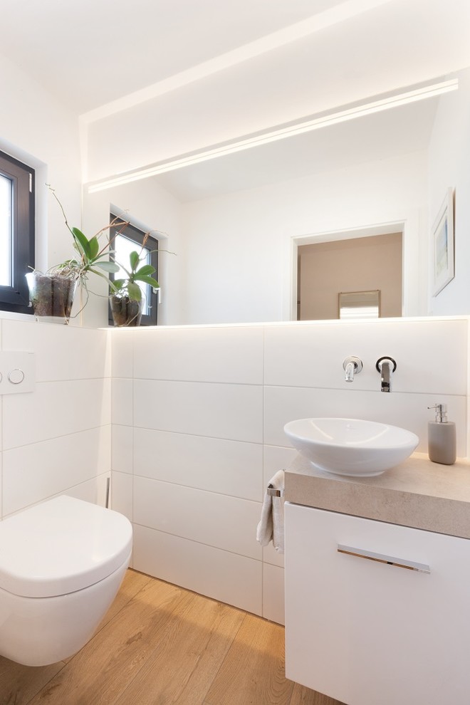 Design ideas for a small contemporary cloakroom in Stuttgart with flat-panel cabinets, white cabinets, a two-piece toilet, white tiles, ceramic tiles, white walls, light hardwood flooring, a vessel sink, soapstone worktops, brown floors and brown worktops.