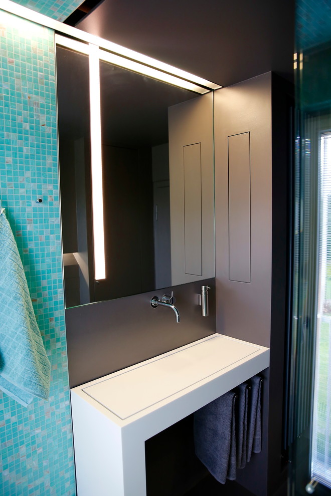 Стильный дизайн: туалет среднего размера в стиле модернизм с плиткой мозаикой, раковиной с несколькими смесителями, столешницей из искусственного камня, синей плиткой и открытыми фасадами - последний тренд