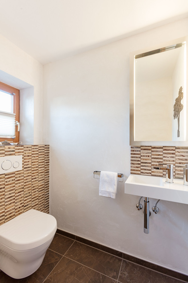 Kleine Moderne Gästetoilette mit braunen Fliesen, Marmorfliesen, weißer Wandfarbe, Kalkstein, braunem Boden, Wandtoilette mit Spülkasten und Wandwaschbecken in München