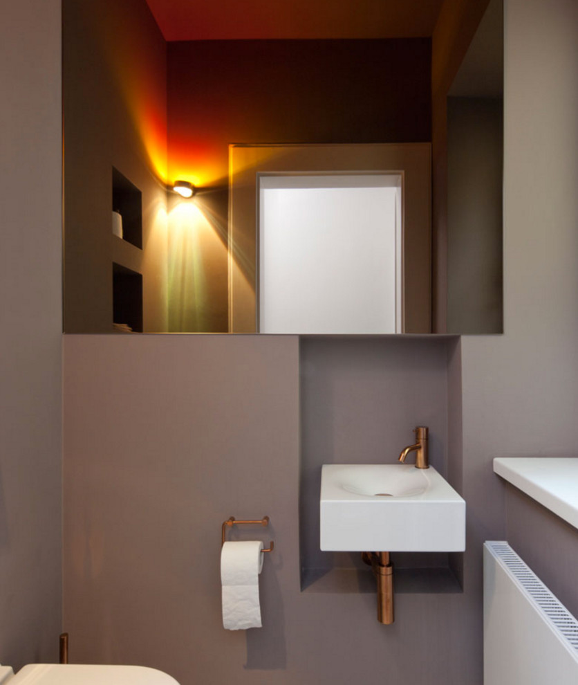 Inredning av ett 60 tals mellanstort toalett, med grå väggar och ett väggmonterat handfat