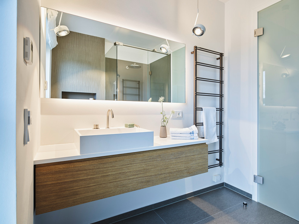 Photo of a small cloakroom in Frankfurt with flat-panel cabinets, a floating vanity unit, medium wood cabinets, a wall mounted toilet, beige tiles, ceramic tiles, white walls, ceramic flooring, a vessel sink, wooden worktops, brown floors and white worktops.