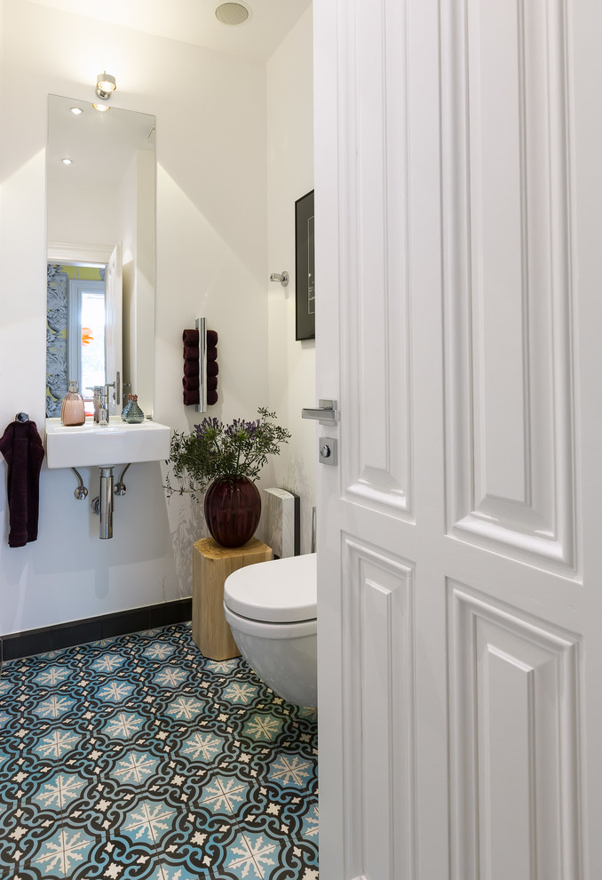 Immagine di un piccolo bagno di servizio minimal con WC sospeso, pareti bianche, pavimento in cementine, lavabo sospeso e pavimento multicolore