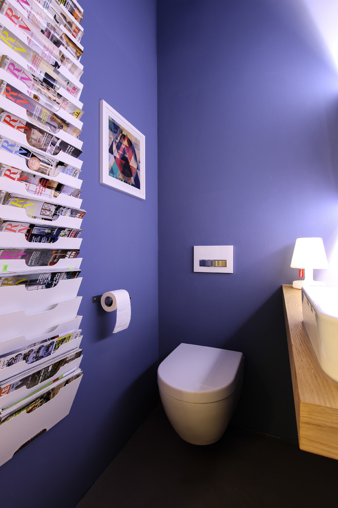 Small trendy powder room photo in Frankfurt with a two-piece toilet, blue walls, a vessel sink and wood countertops