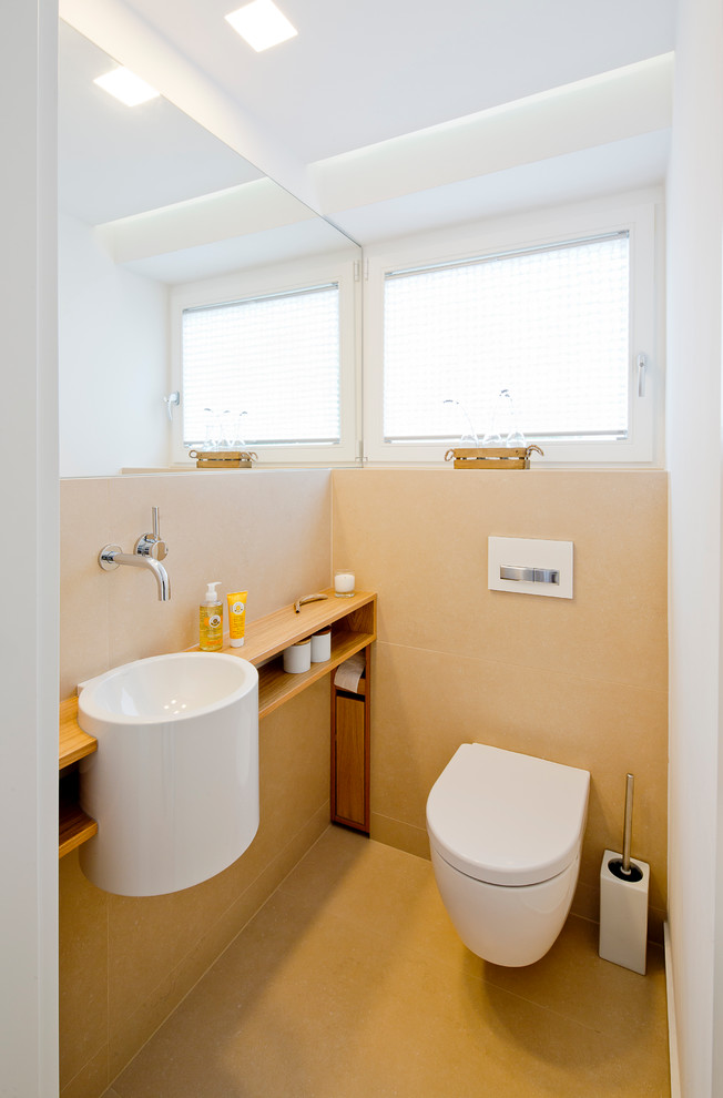 Small contemporary cloakroom in Dusseldorf with open cabinets, a wall mounted toilet, beige walls, wooden worktops, beige tiles, a wall-mounted sink, stone tiles, beige floors and brown worktops.