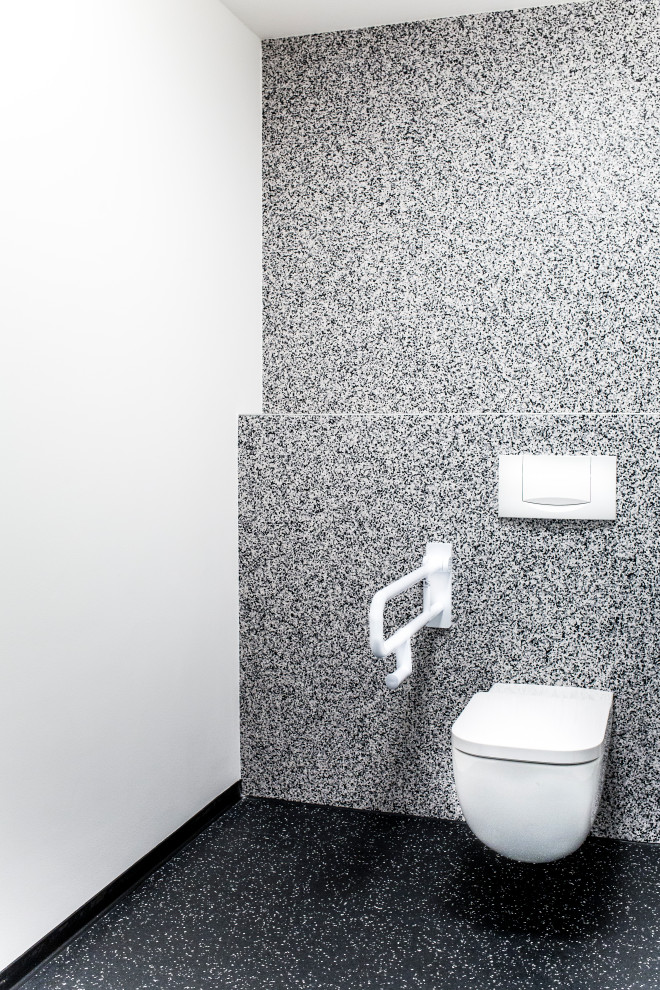 Idéer för mellanstora funkis toaletter, med en toalettstol med separat cisternkåpa, vita väggar, terrazzogolv, ett väggmonterat handfat och svart golv