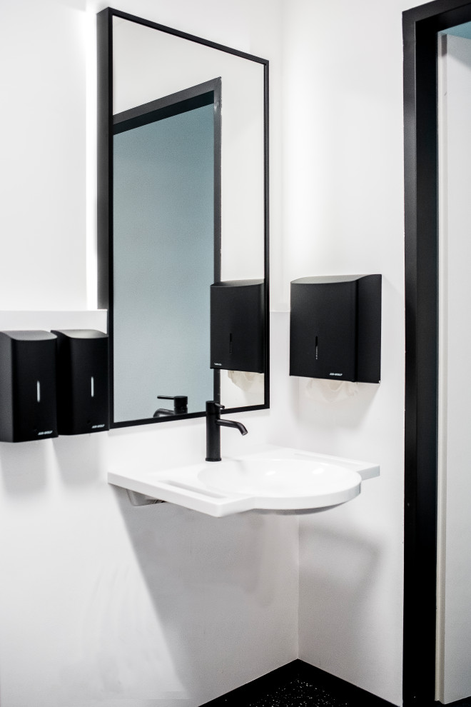 Esempio di un bagno di servizio moderno di medie dimensioni con WC a due pezzi, pareti bianche, pavimento alla veneziana, lavabo sospeso, pavimento nero, mobile bagno sospeso e pannellatura