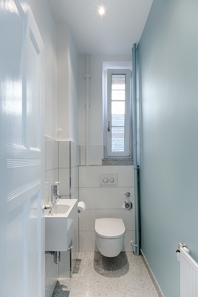 シュトゥットガルトにある小さなコンテンポラリースタイルのおしゃれなトイレ・洗面所 (白いタイル、青い壁、壁付け型シンク、テラゾーの床) の写真