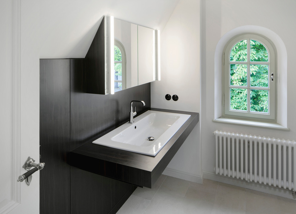 Foto de aseo clásico con puertas de armario de madera en tonos medios, lavabo encastrado, encimera de madera y encimeras negras