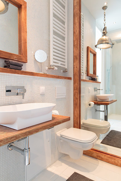 Aménagement d'un WC suspendu industriel de taille moyenne avec un carrelage blanc, mosaïque, une vasque et un plan de toilette en bois.