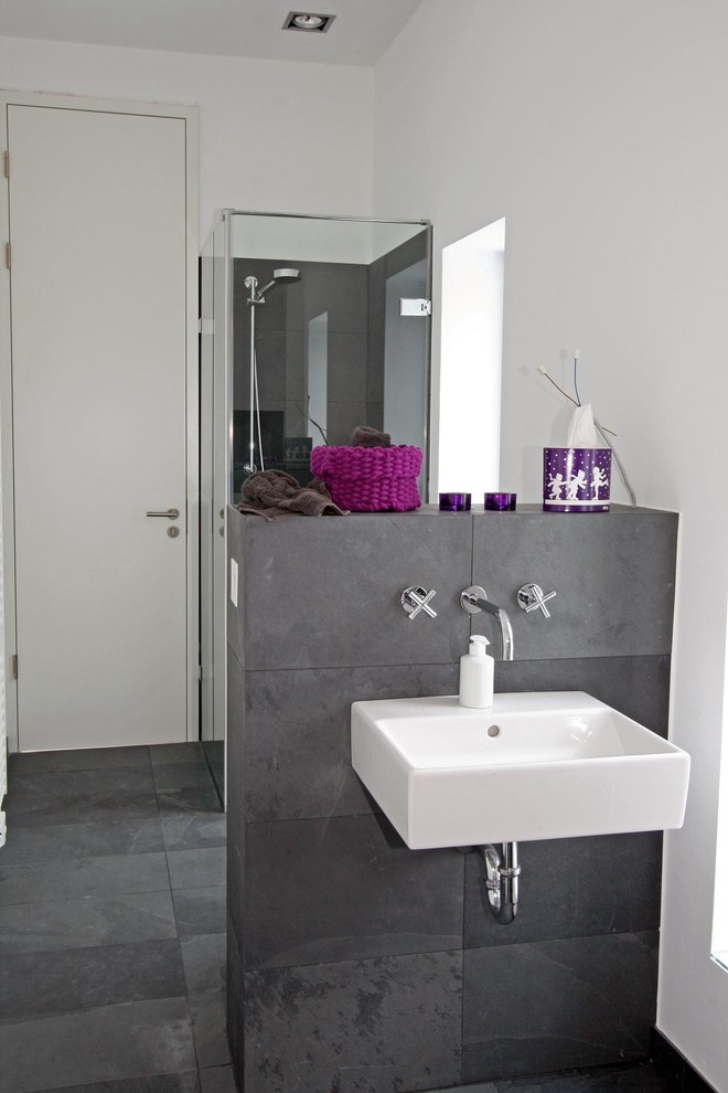 Свежая идея для дизайна: туалет среднего размера в современном стиле с серой плиткой, белыми стенами, подвесной раковиной, полом из сланца и каменной плиткой - отличное фото интерьера