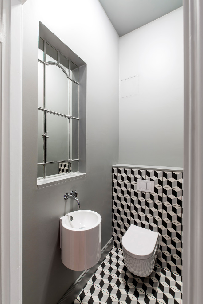 Réalisation d'un petit WC suspendu design avec un mur gris, carreaux de ciment au sol, un lavabo suspendu et un sol multicolore.