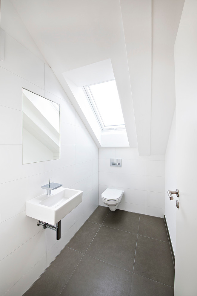 Esempio di un bagno di servizio contemporaneo di medie dimensioni con WC sospeso, piastrelle bianche, piastrelle grigie, pareti bianche e lavabo sospeso