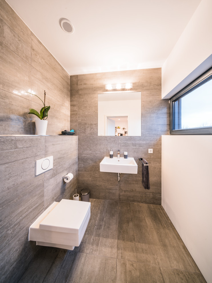 Immagine di un piccolo bagno di servizio design con WC a due pezzi, piastrelle beige, piastrelle marroni, pareti bianche, lavabo sospeso e pavimento beige