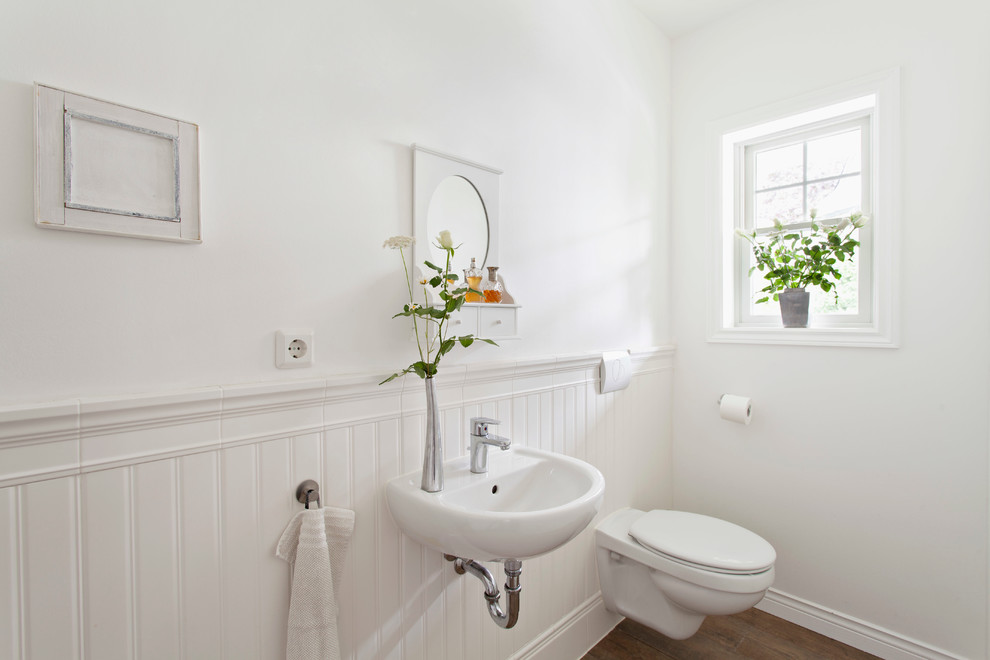 На фото: туалет в стиле кантри с подвесной раковиной, инсталляцией, белыми стенами и паркетным полом среднего тона