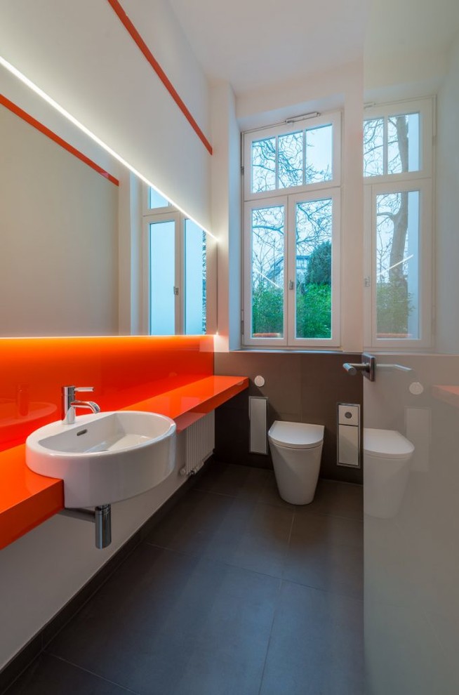 Immagine di un piccolo bagno di servizio contemporaneo con WC sospeso, piastrelle marroni, piastrelle di cemento, pareti bianche, pavimento in cementine, lavabo integrato e pavimento marrone