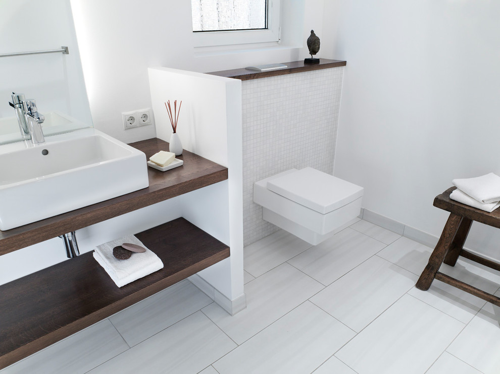 Idéer för ett mellanstort modernt toalett, med öppna hyllor, skåp i mörkt trä, en vägghängd toalettstol, vit kakel, mosaik, vita väggar, klinkergolv i keramik, ett fristående handfat, bänkskiva i akrylsten och vitt golv