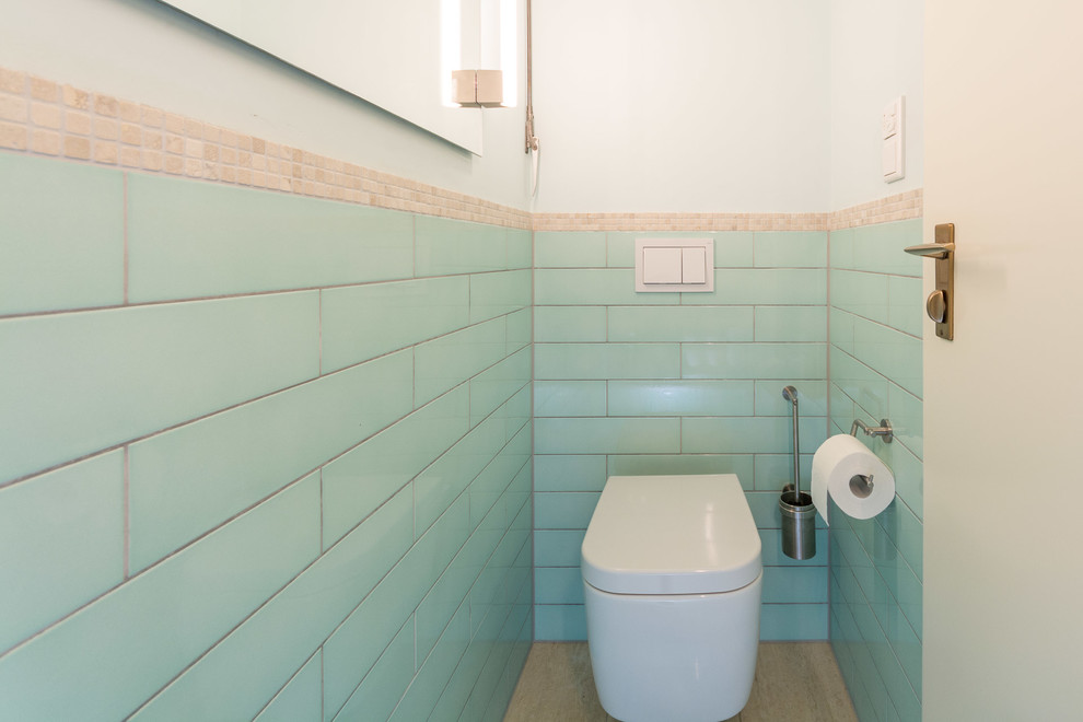 ミュンヘンにある小さなコンテンポラリースタイルのおしゃれなトイレ・洗面所 (壁掛け式トイレ、青いタイル、セラミックタイル、青い壁、ライムストーンの床、ベッセル式洗面器、タイルの洗面台、ベージュの床) の写真