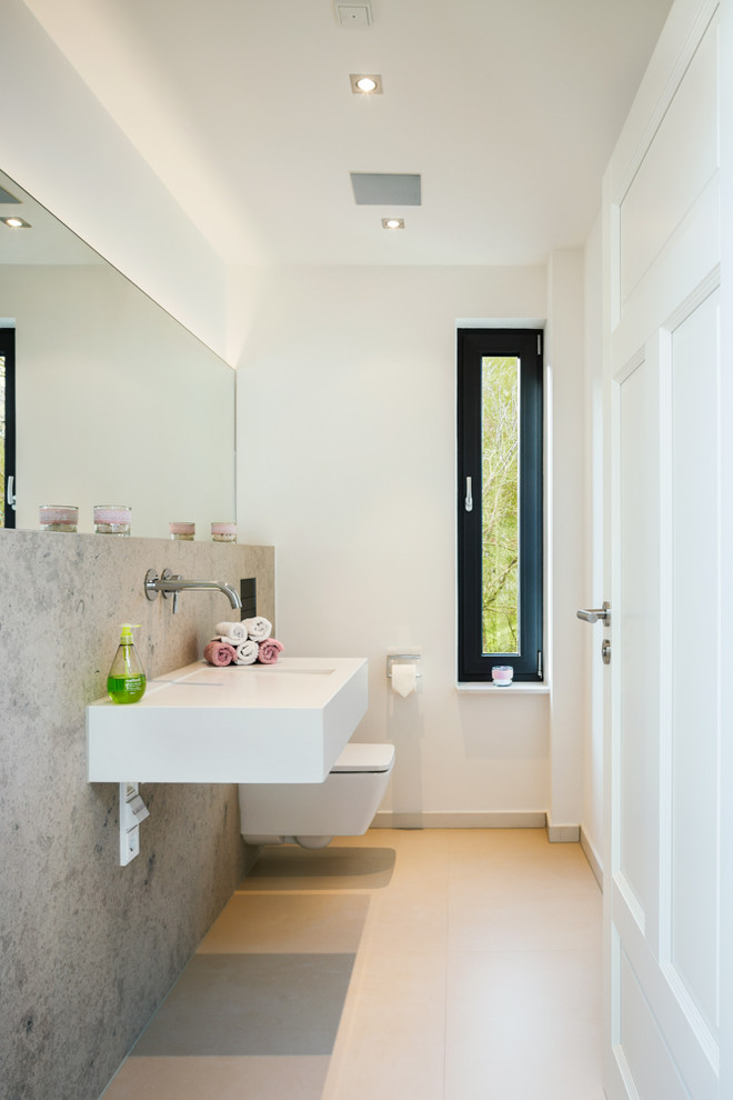 Idée de décoration pour un WC suspendu design de taille moyenne avec un carrelage beige, un mur blanc, un sol en carrelage de céramique, un lavabo suspendu et un sol beige.