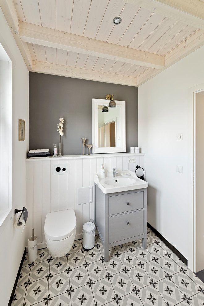 Cette image montre un petit WC suspendu rustique avec un placard à porte plane, des portes de placard grises, un sol en carrelage de porcelaine, une vasque, un plan de toilette en bois, un sol gris et un mur gris.