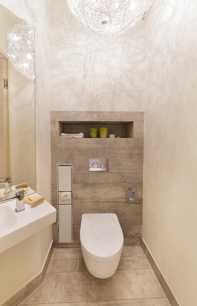 Cette photo montre un petit WC et toilettes tendance avec WC séparés, un carrelage beige, un mur blanc, un lavabo suspendu et un sol beige.