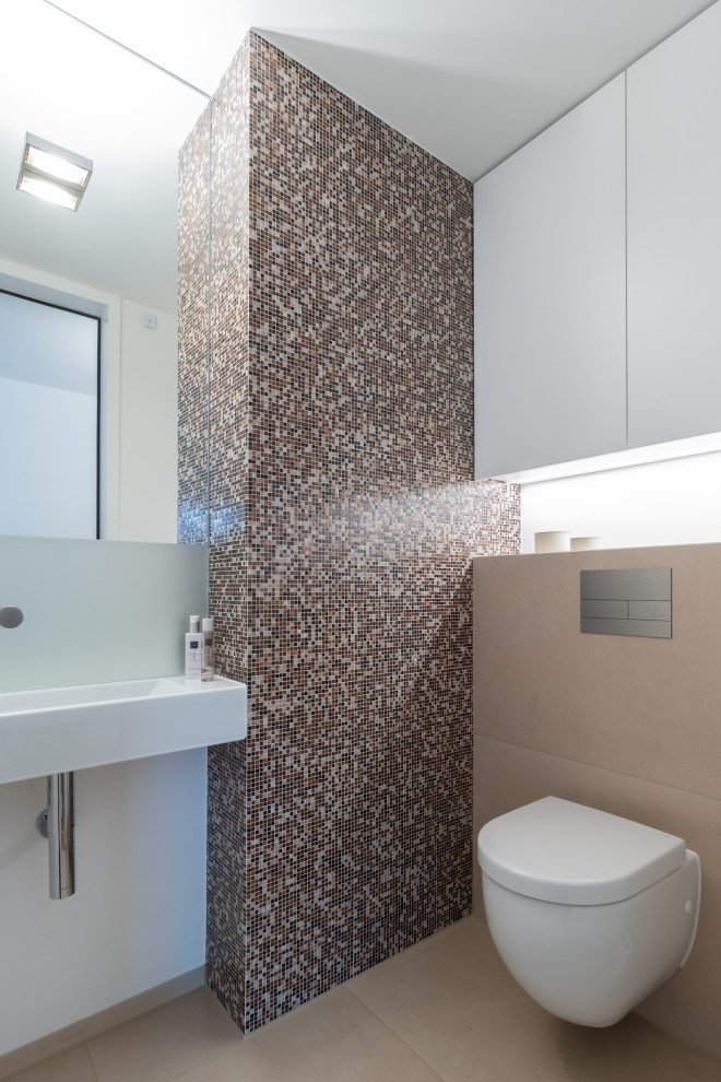 Стильный дизайн: туалет в стиле модернизм с стеклянной плиткой, подвесной раковиной, инсталляцией, разноцветной плиткой, белыми стенами и бежевым полом - последний тренд