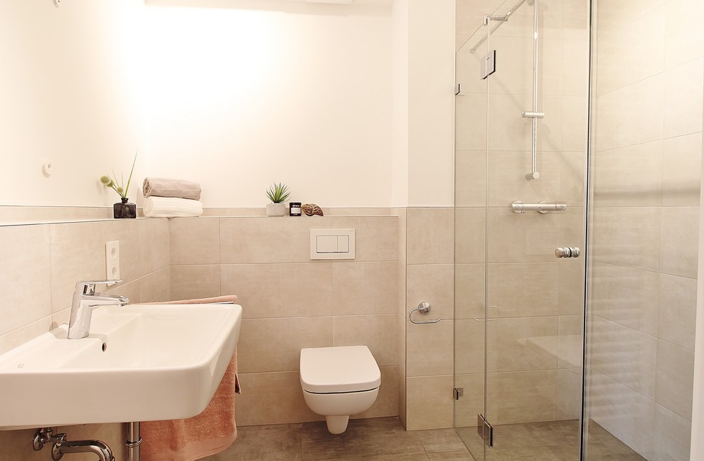 Inspiration för mellanstora moderna badrum, med en vägghängd toalettstol, beige kakel, porslinskakel, vita väggar, cementgolv, ett väggmonterat handfat och brunt golv