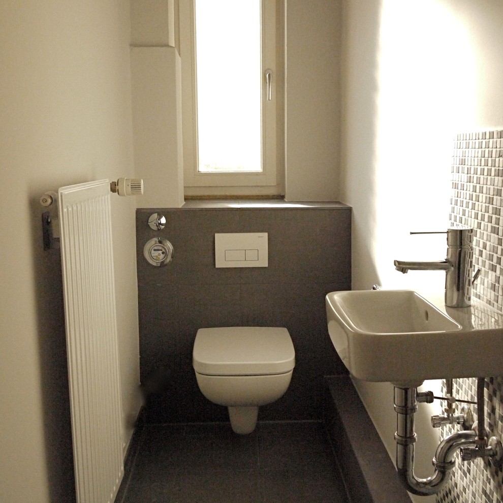 Inspiration pour un petit WC et toilettes design avec WC séparés, un carrelage gris, un carrelage de pierre, un mur blanc et une grande vasque.