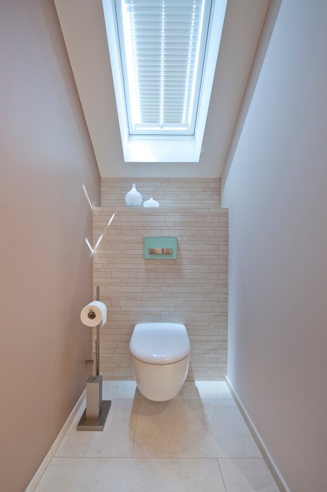 Kleine Moderne Gästetoilette mit Wandtoilette, beigen Fliesen, Steinfliesen und beiger Wandfarbe in München