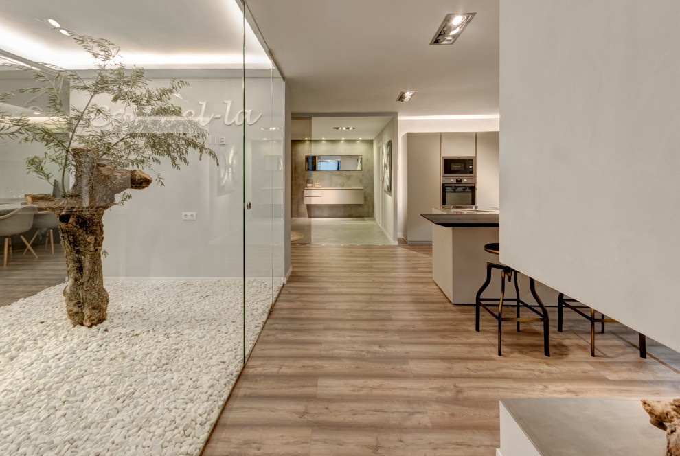 Imagen de galería minimalista grande con suelo de madera en tonos medios, chimenea lineal, marco de chimenea de metal, techo con claraboya y suelo marrón