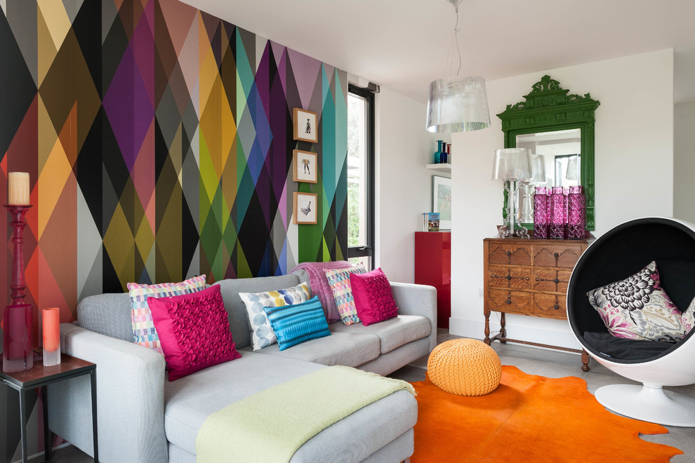 Cette image montre une salle de séjour bohème fermée avec un mur multicolore et un sol gris.