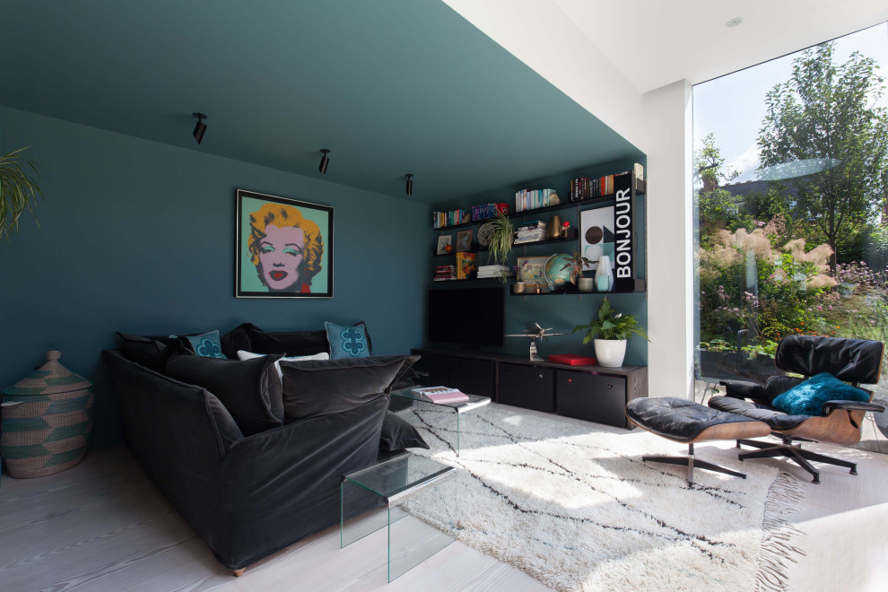 Großer, Offener Moderner Hobbyraum ohne Kamin mit blauer Wandfarbe, hellem Holzboden, freistehendem TV und weißem Boden in London