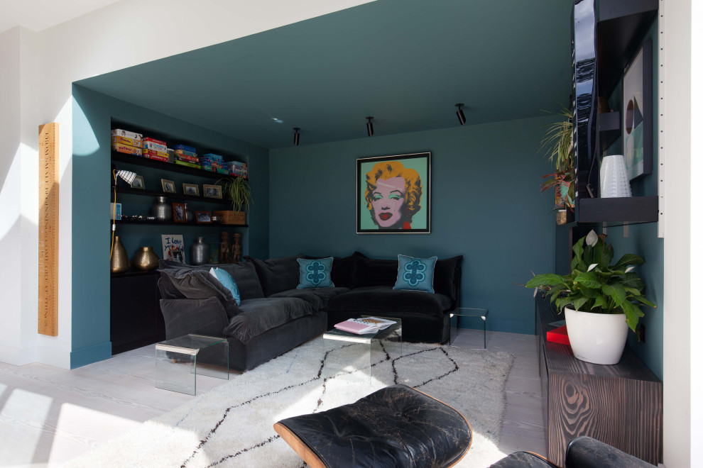 Inredning av ett modernt stort allrum med öppen planlösning, med ett spelrum, blå väggar, ljust trägolv, en fristående TV och vitt golv
