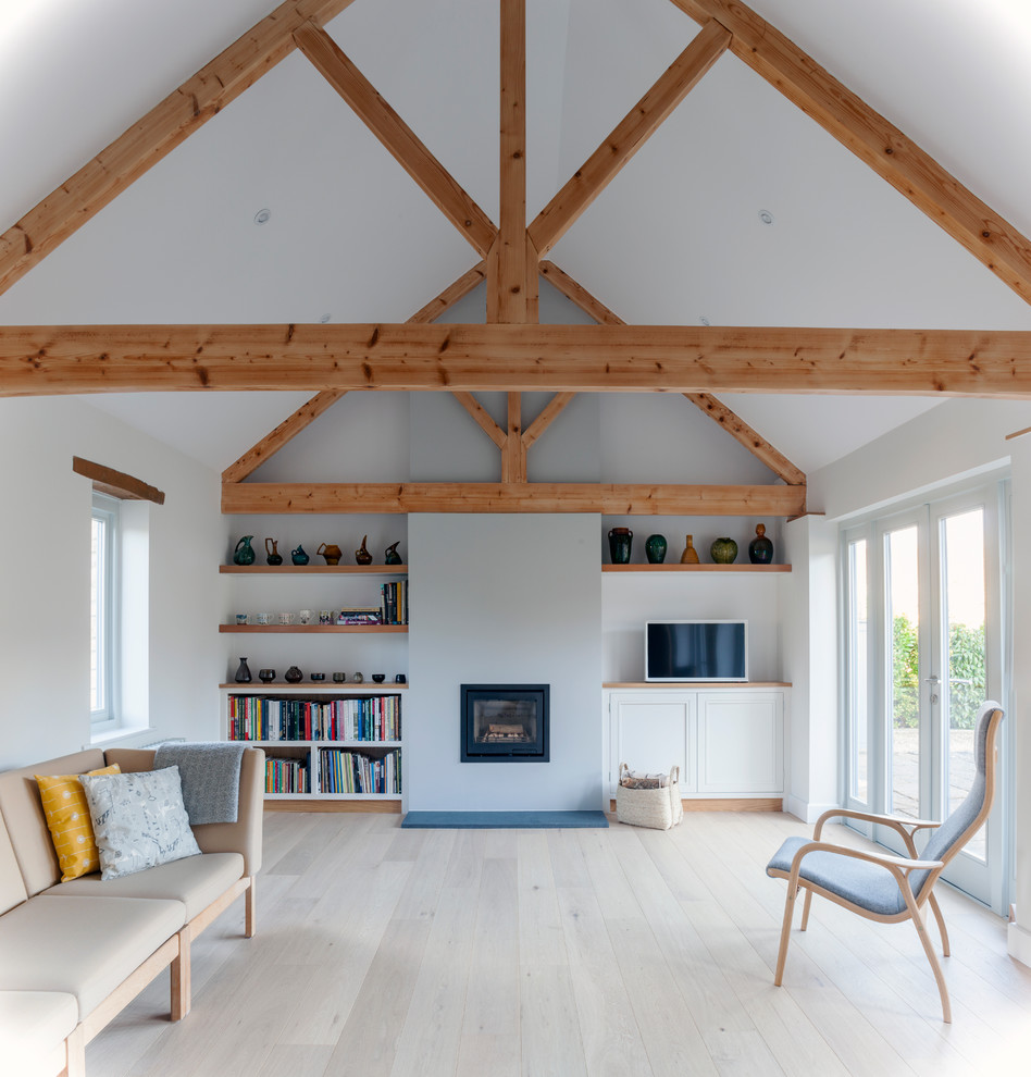 Mittelgroßes, Abgetrenntes Skandinavisches Wohnzimmer mit beigem Boden, weißer Wandfarbe, Kaminumrandung aus Backstein, freistehendem TV, gebeiztem Holzboden und Kamin in Wiltshire