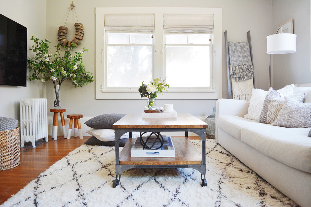 Ejemplo de sala de estar clásica renovada con paredes blancas, suelo de madera en tonos medios, televisor colgado en la pared y suelo marrón