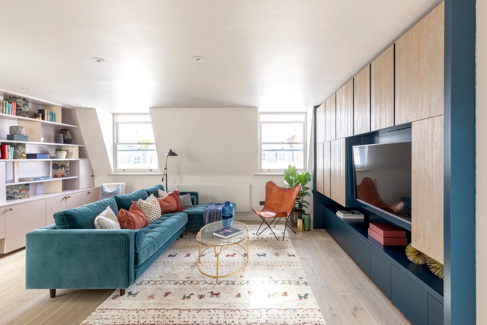 Imagen de sala de estar con biblioteca actual sin chimenea con paredes blancas, suelo de madera clara y pared multimedia