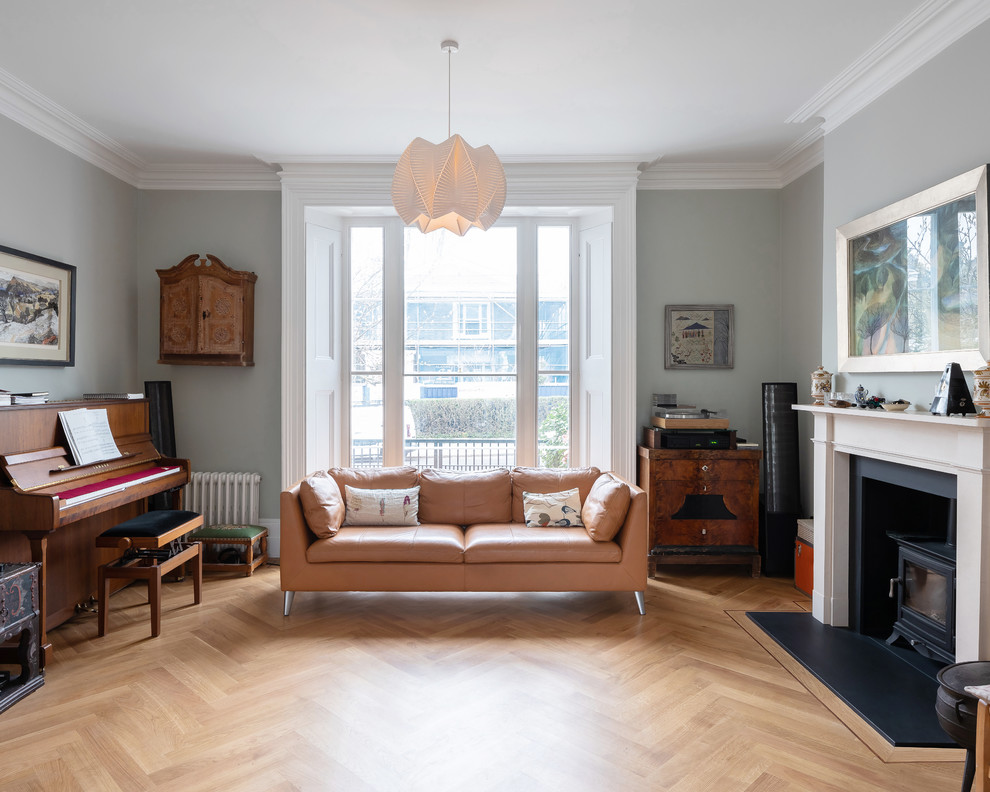 Klassisches Musikzimmer mit grauer Wandfarbe, braunem Holzboden, Kaminofen und braunem Boden in London