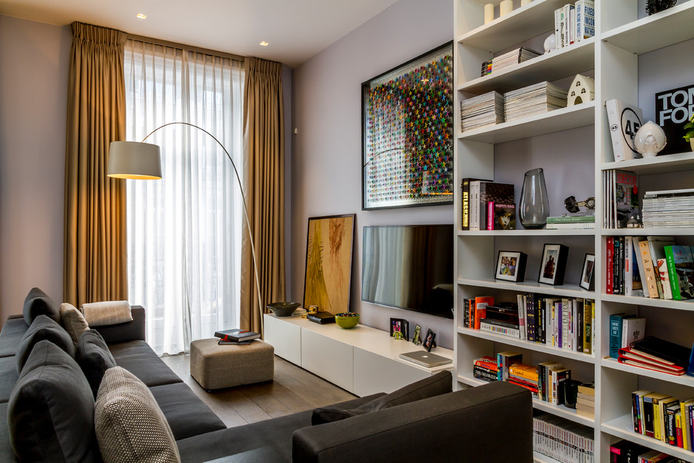 Идея дизайна: изолированная гостиная комната в современном стиле с фиолетовыми стенами, светлым паркетным полом и телевизором на стене