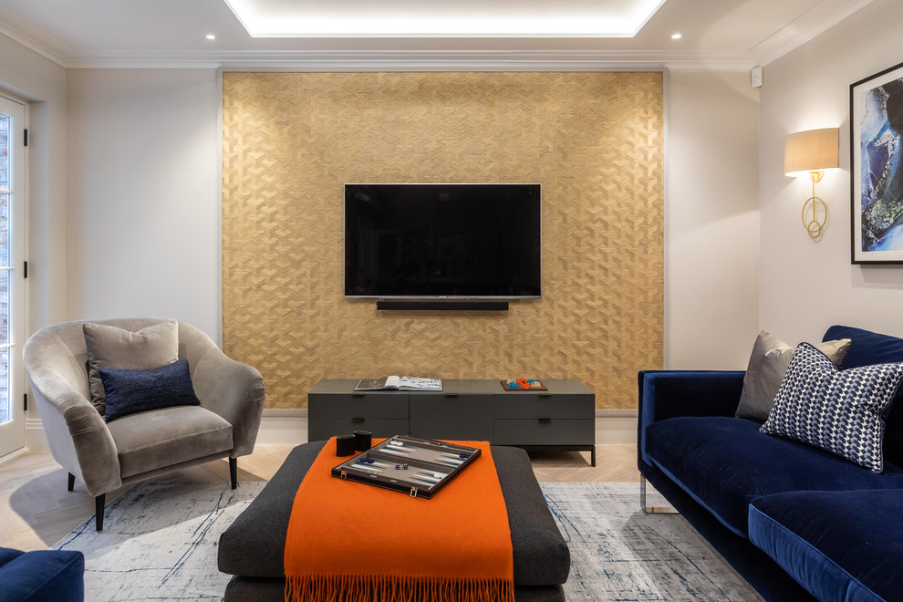 На фото: гостиная комната в современном стиле с бежевыми стенами, светлым паркетным полом, телевизором на стене и синим диваном без камина с