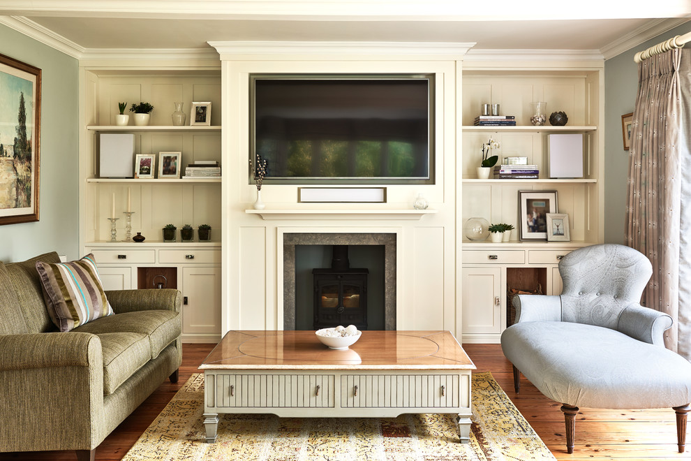 Klassisches Wohnzimmer mit grauer Wandfarbe, braunem Holzboden, Kaminofen und Multimediawand in Wiltshire