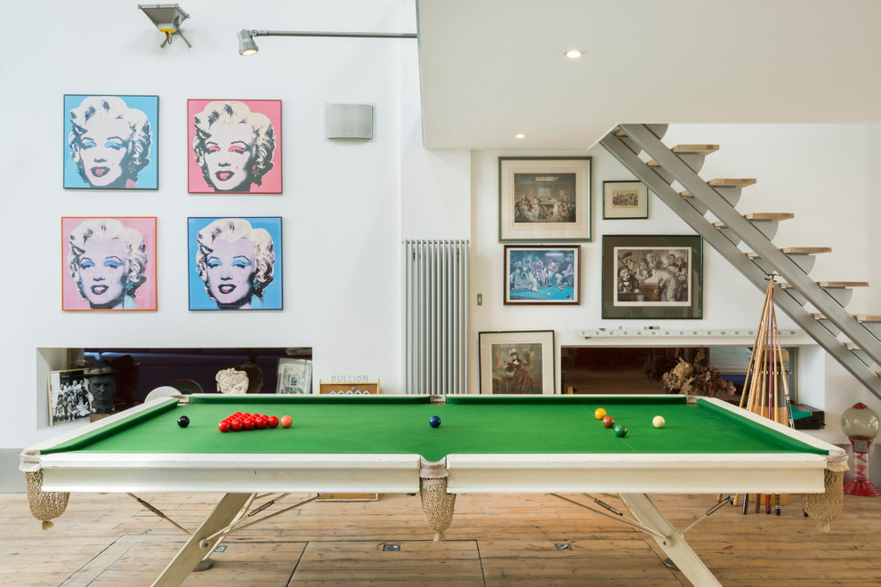 This is an example of a contemporary games room in London with white walls and light hardwood flooring.