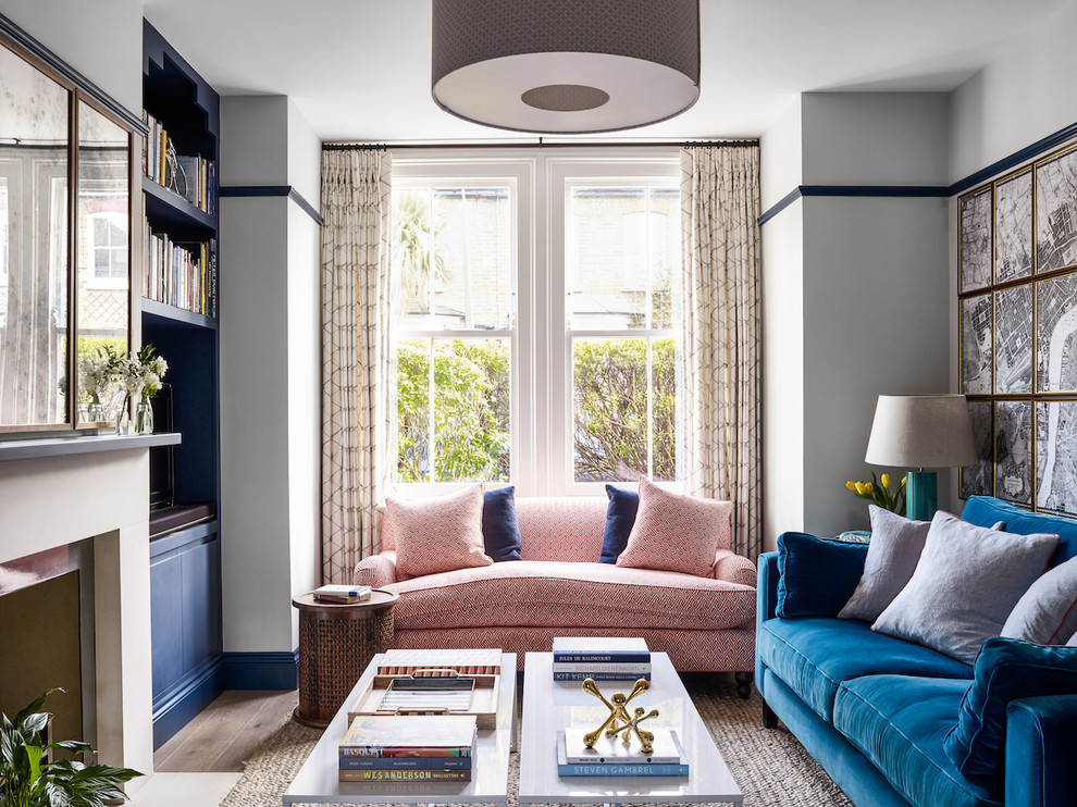 Источник вдохновения для домашнего уюта: гостиная комната в викторианском стиле с с книжными шкафами и полками, белыми стенами, стандартным камином, фасадом камина из металла и синим диваном