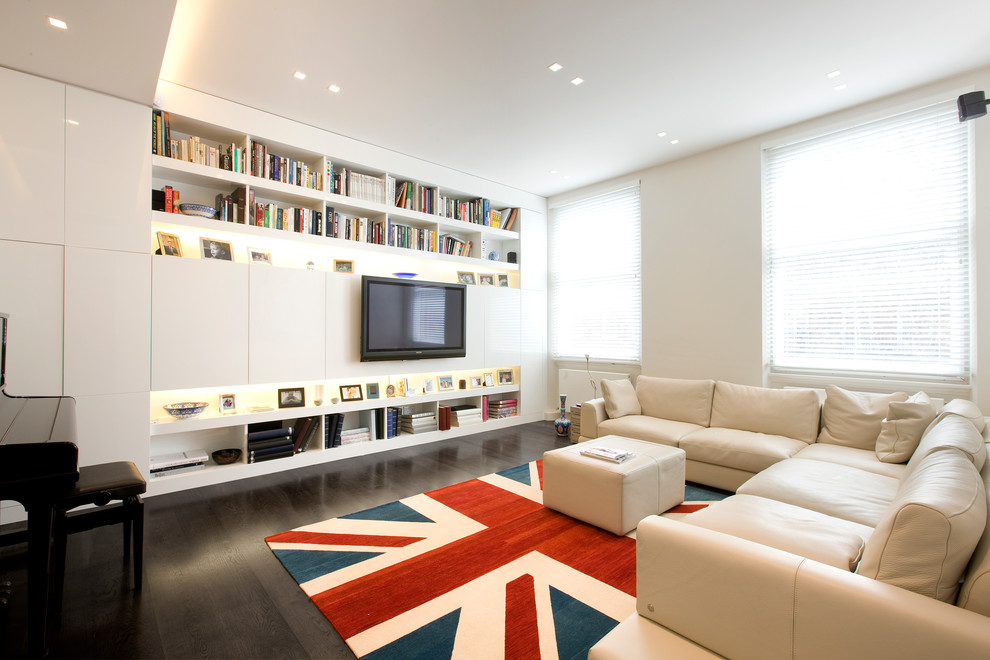 Imagen de sala de estar actual con paredes beige, suelo de madera oscura, televisor colgado en la pared y suelo marrón